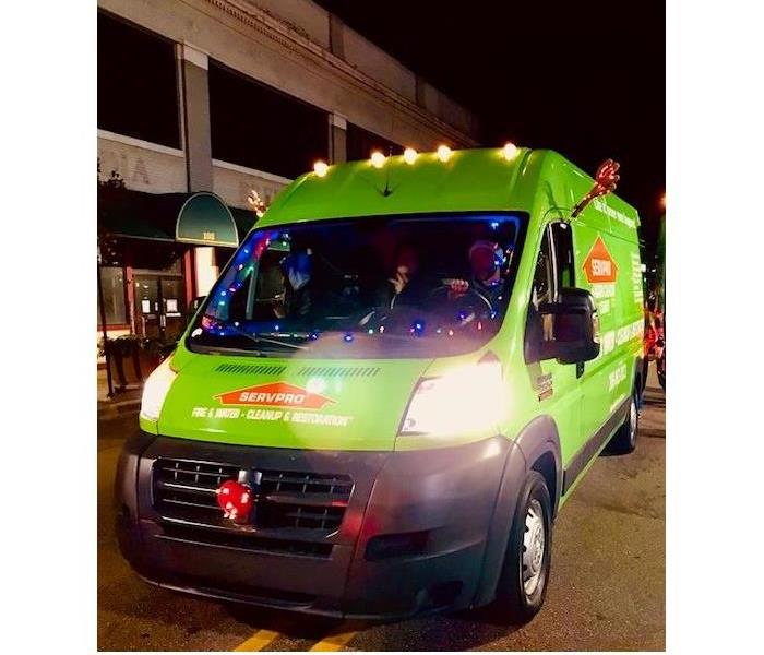 Green SERVPRO van decorated with lights participating in Christmas parade.